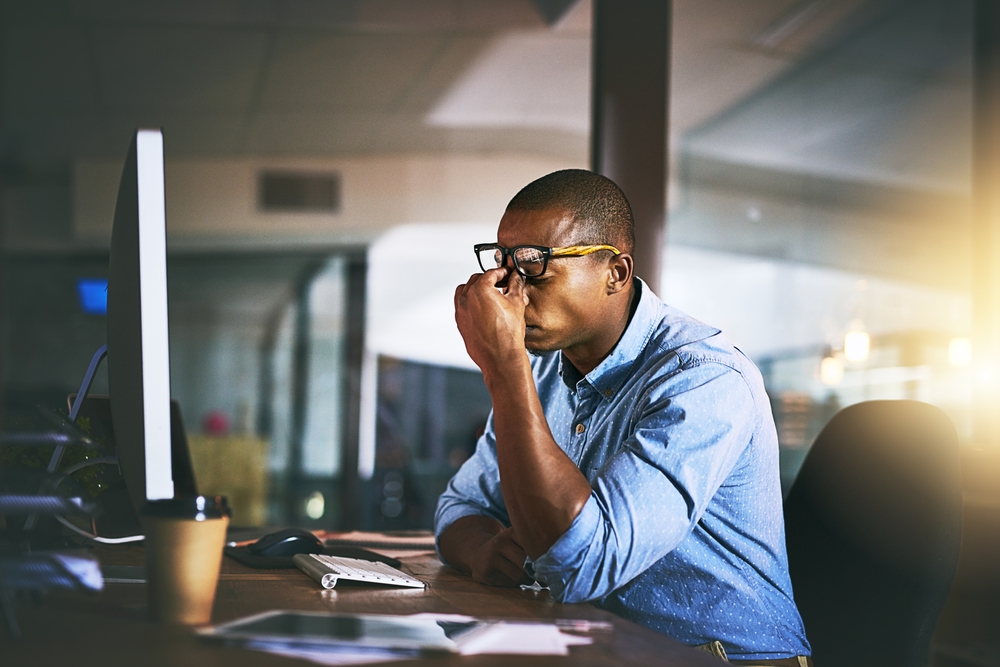 Black business man, stress and fatigue in night, office and headache by computer for project deadline.