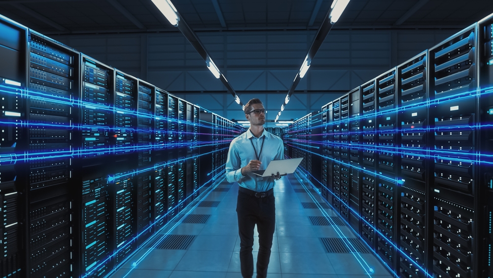 Futuristic Concept: Data Center Chief Technology Officer Holding Laptop, Standing In Warehouse