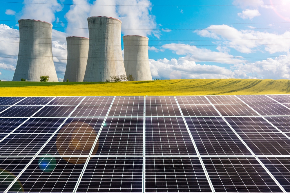 Solar panels with a nuclear power plant in the background. Comparison of two different energy sources.